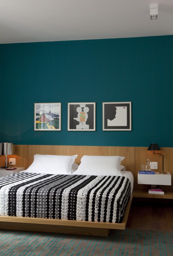 A suíte do casal foi pintada de verde petróleo que ressaltou os quadros e a madeira da cama feita sob projeto.