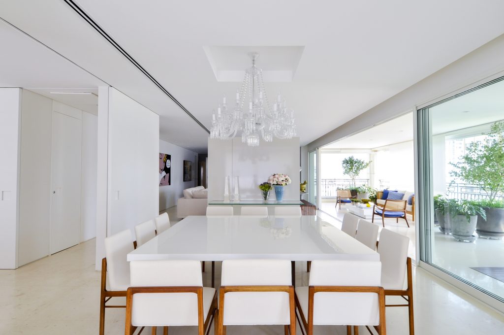 Localizado na ponta do living, o jantar é mobiliado com uma ampla mesa laqueada e cadeiras com pés de madeira, servidas pelo aparador de vidro (Vidroart) onde estão dois vasos Lalique. Ao centro, o belo lustre Baccarat. 