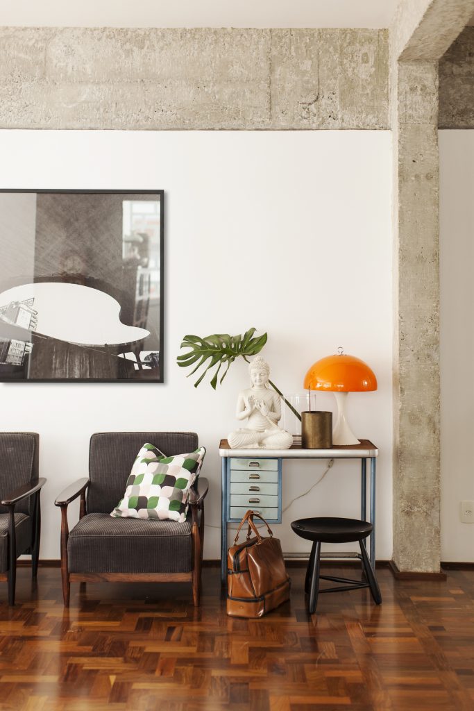 Para compor o décor, Maurício Arruda brincou com a mistura de retrô e contemporâneo. A inspiração vintage veio do próprio imóvel, que teve seu piso de ipê e paredes de concreto originais trazidas à tona, e dos móveis e peças antigos do acervo dos clientes. A cozinha agora é integrada na sala pela bancada complementada pelas banquetas Tolix, servindo para refeições rápidas.