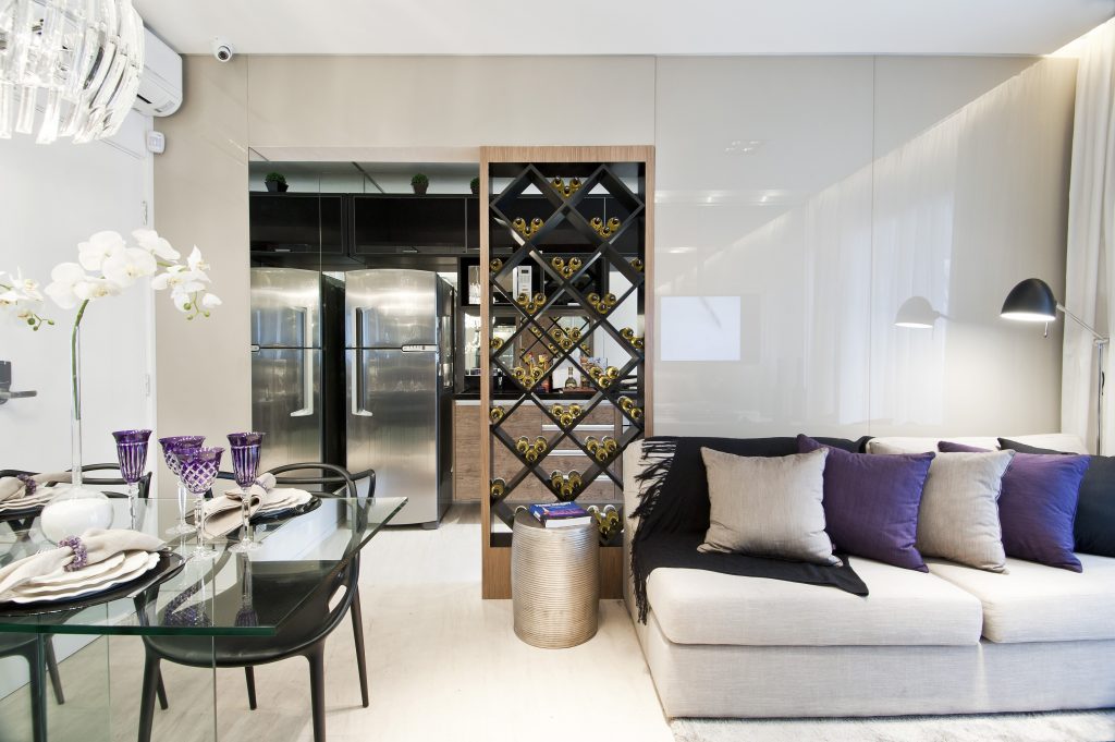 No studio de 40 m2, cada qual em seu lugar sem perder área e circulação. O pequeno living integra jantar e estar com confortável sofá revestido de linho, compondo com xale e almofadas coloridas e se relaciona com a cozinha sutilmente separado pela adega em marcenaria.