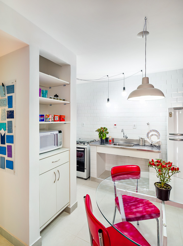 Na cozinha, a marcenaria otimizou o espaço. Devido às dimensões restritas do ambiente, evitaram-se armários fechados, sendo incluídos nichos para abrigar os eletrodomésticos e utensílios. Os revestimentos antigos foram substituídos por porcelanato Beton White (Eliane) em tons neutros, fazendo fundo para detalhes em cores como as cadeirinhas. 