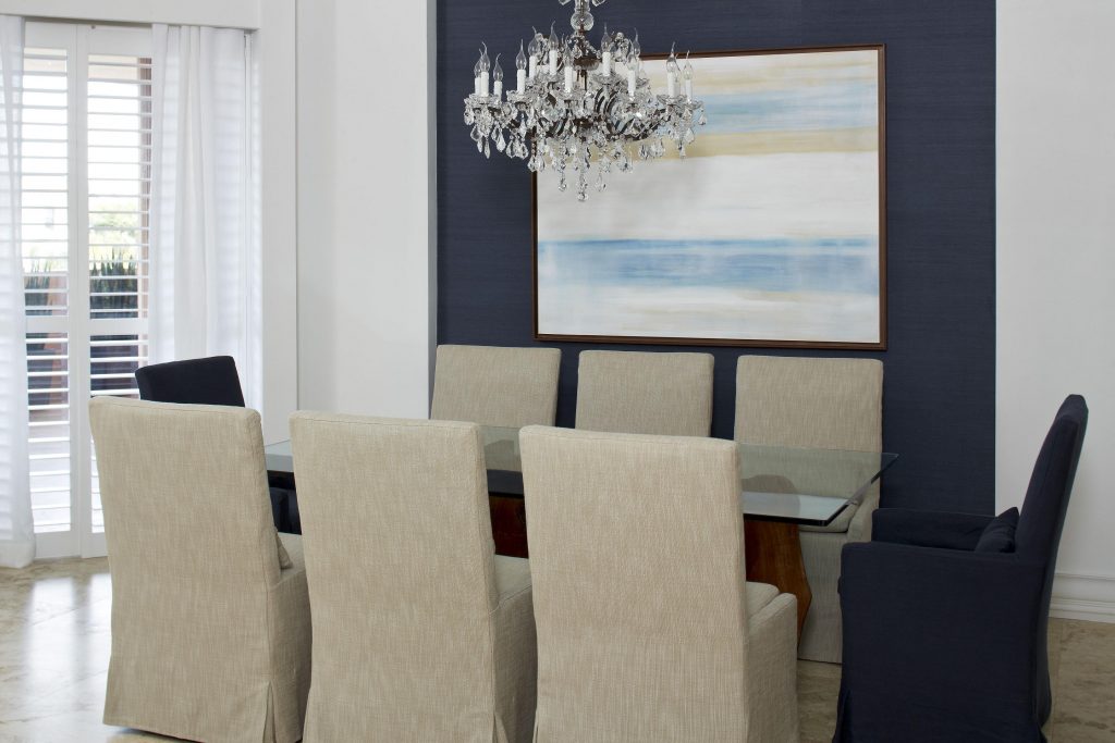 No jantar, mais algumas pinceladas de cor azul sobre a parede e duas poltronas. A mesa em vidro (Artefacto) traz leveza e o lustre em cristal, elegância, destacado também pela tela de Fernanda Dabus.