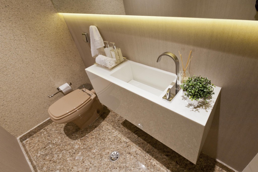 No banheiro com piso de granito e vaso marrom originais, a cuba de marmoglass o papel de parede (Orlean) e o espelho com iluminação embutida criam uma composição atual.