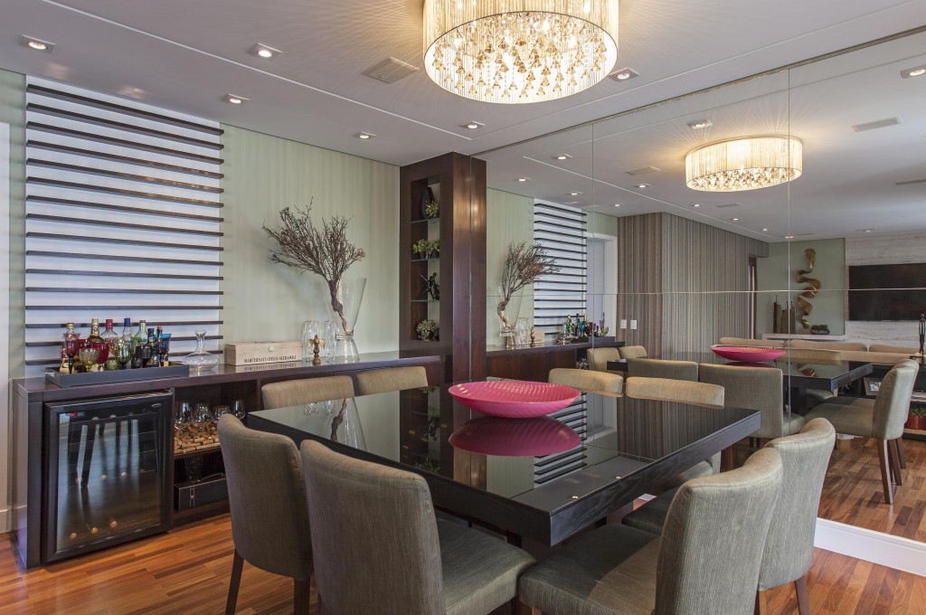 A sala de jantar conta com mesa revestida de lâmina de carvalho ebanizada e cadeiras estofadas Combina-se a ela o aparador de imbuia escurecida com painel decorativo (Decor City) que faz as vezes de bar. Ao lado, os espelhos duplicam o ambiente com lustre de cristal fumê.