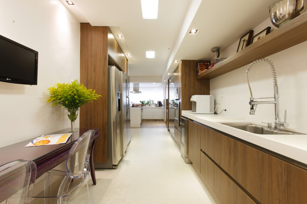 A cozinha, conectada à varanda, foi bem aproveitada com a marcenaria planejada da Florense, dando espaço até para o canto de apoio, criado com a mesa da cliente, restaurada com pintura. 