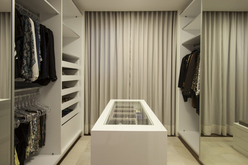 Em vez de mais quarto, os moradores optaram por ter grandes closets individuais (Blanco Design) como este com armários, divisões e ilha central que facilita a organização.